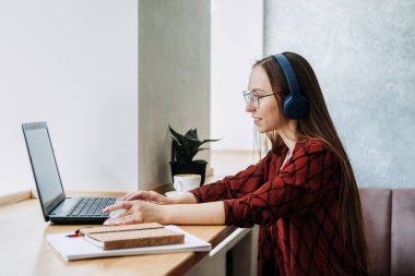 Outsourcing IT Projects, remote work, young professionals. female young programmer, developer working with online Projects on laptop in cafe