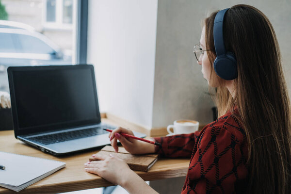 Outsourcing IT Projects, remote work, young professionals. female young programmer, developer working with online Projects on laptop in cafe