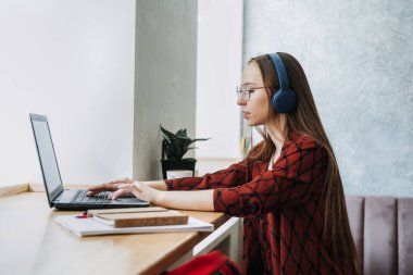 Part Time Business, Part-time job or side hustles concept. Young confident woman student in headset working with laptop in cafe