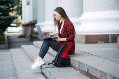 Online jobs for college students. Young woman student girl searching job with laptop outdoors in summer day. Side hustle for students