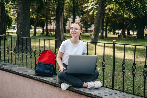 Student loan, Student finance for undergraduates. Outdoor portrait of happy student girl with laptop, papers and books near college, university