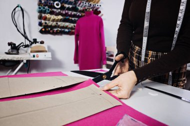 Hand Cutting Pattern and Fabric Pieces. Fashion Design. Female tailor, seamstress working with sewing pattern on table in tailor shop, seamstress studio