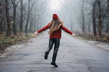 Weekend breaks and getaways in forests. Stay close to nature. Young woman in red hat and sweater walking in pine forest