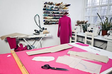Start Sewing Business at Home, creating clothing patterns, performing alterations and tailoring. Seamstress working with sewing pattern on table in tailor shop