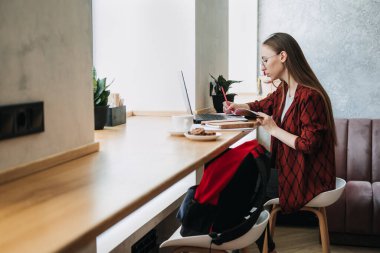 Freelancing for beginners, working as freelancer, Flexible working hours. Young candid woman freelancer working with laptop and documents in cafe, coworking workplace