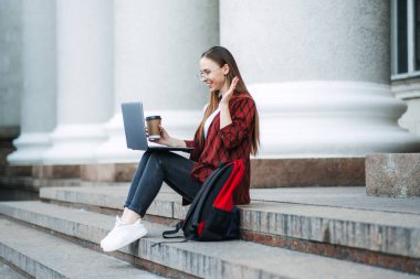 Online tutor, tutoring jobs for college students. How earn extra money while learning. Side hustling for students. Outdoor portrait of student girl with laptop having video call