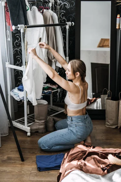 Organize closet, decluttering wardrobe. Young woman decluttering wardrobe and choosing clothes in her bedroom