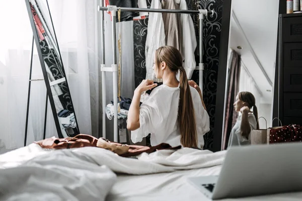 Organize closet, decluttering wardrobe. Young woman decluttering wardrobe and choosing clothes in her bedroom