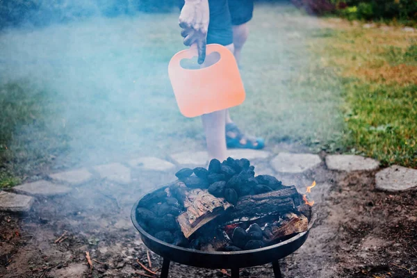 How to Use a Charcoal Grill. Man with Plastic BBQ Hand Fan near Charcoal Grill Fire. Barbeque Plastic BBQ Hand Fan Starter and fire with Smoker