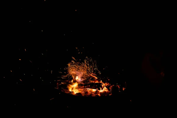 Campfire flame sparks isolated on black background. Fire flames heat energy heap in the night. Fire sparkles isolated on black background