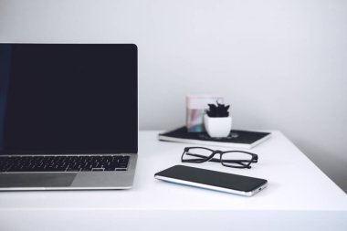 Çevrimiçi iş fikirleri. Küçük İşletmeler İnternette Başlıyor. Boş ekran dizüstü bilgisayarı, cep telefonu, kalem, beyaz çalışma masasında modern çalışma alanı