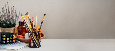 Resim arkaplan web afişi çiziliyor. Renkli boyalar, fırçalar, kırtasiye malzemeleri, çizim ve zanaat malzemeleri. Yaratıcı eğitim ortamı, sanatçı masası görünümü, kopyalama alanı.