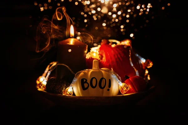 Halloween composition pumpkins and lights glow in the dark among the smoke fog. Halloween pumpkin with word Boo on black background in smoke