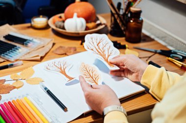 Yetişkinler için sonbahar sanatı. Sonbahar sanat yaratıcı kolajı. Kalemlerle sonbahar ağaçları çizen ve kağıttan kolaj kesen kadının yüzsüz portresi.