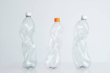 3 büyük sıkılmış, kapalı kapaklı plastik su şişesi. Stüdyo çekimi, beyaz, insan yok..