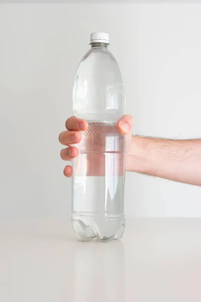 大的透明塑料水瓶 瓶盖紧密 由无法辨认的白人男性手握住 近距离拍摄 被白色隔离 — 图库照片