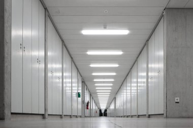 Uzun ve boş bir iç koridor. Kaybolan perspektif, parlak neon ışıklar, dikey dolaplar yan duvarda. Yeraltında, insan yok..