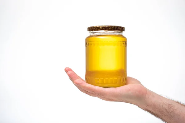 新鲜的金黄色蜜蜂蜂蜜在玻璃瓶里 由白人男性的手握住 特写镜头 白色背景隔离 — 图库照片