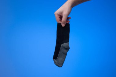 Beyaz bir erkeğin elinde tek bir kuru ve temiz pamuk çorap. Stüdyo çekimini kapat, mavi arkaplanda izole edilmiş..