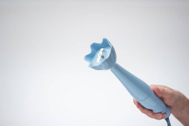Küçük plastik el yapımı blender erkek eliyle tutulmuş. Stüdyo çekimini kapat, beyaz arkaplanda izole edilmiş..