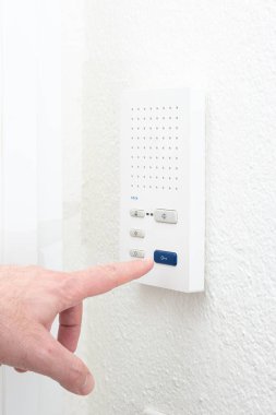 Beyaz erkek parmağı, dahili iletişim cihazını içeriden yönetiyor. İç tarafı yakın çekim, yüzü yok..