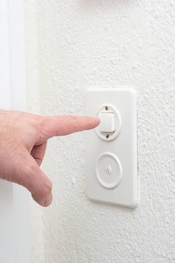 Beyaz erkek parmağı dairenin içindeki ışık düğmesine basıyor. İç tarafı yakın çekim, yüzü yok..