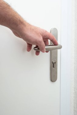 Beyaz bir erkek, içeriden kapı kolu açıyor. İç tarafı yakın çekim, yüzü yok...