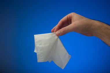 Beyaz kağıt peçete ya da beyaz bir erkeğin elinde tuttuğu mendil. Stüdyo çekimini kapat, mavi arkaplanda izole edilmiş..