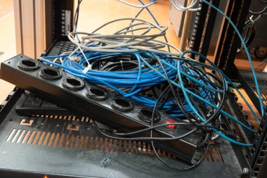 Dağınık kablo grubu. Güç, uzatma kablosu, ethernet kabloları birbirine dolanmış. Endüstriyel binada geçiyor, insan yok..