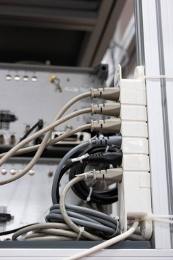 Tam güç uzatma kablosu. Prizlere bağlı, maksimum kapasitede, aşırı yükleme tehlikesi. Endüstriyel binada geçiyor, insan yok, sığ alan derinliği.