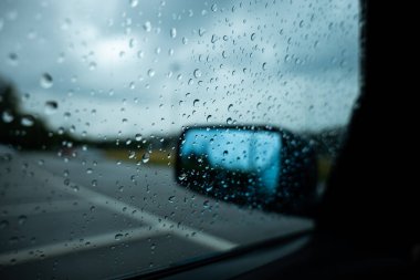 Yağmurlu bir gün ve su damlacıkları soyut bir arabanın camında.