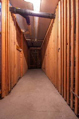 Residential apartment building basement or cellar corridor with wooden doors of tenant's storage places. Dark dimly lit, wide angle, no people.