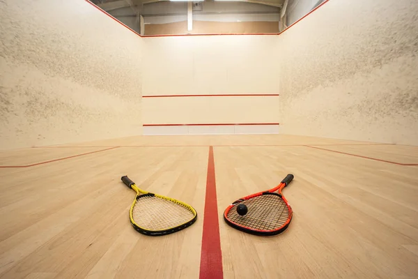 Empty squash court ultra-wide angle view. Racket and ball on the ground, no people.