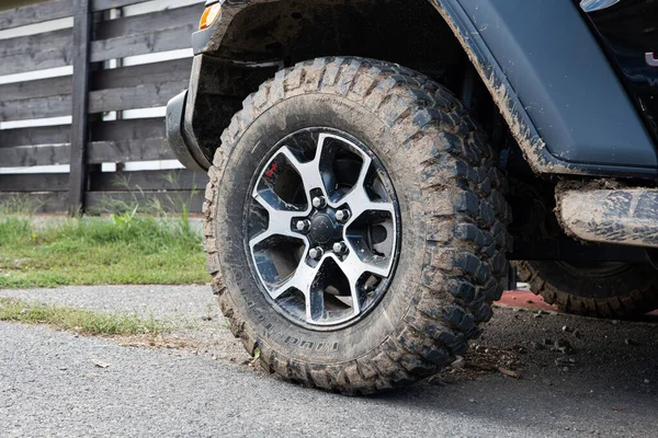 Dried mud on SUV's off-road mud tires. Close up low angle view, no people.
