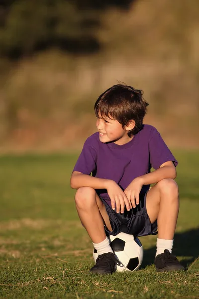 Junge sitzt auf Fußballball — Stockfoto