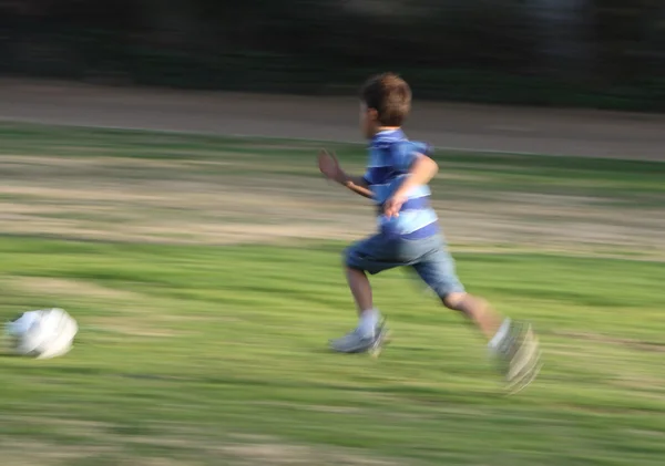 Movimiento borrosa panorámica foto del niño corriendo después de una pelota — Foto de Stock