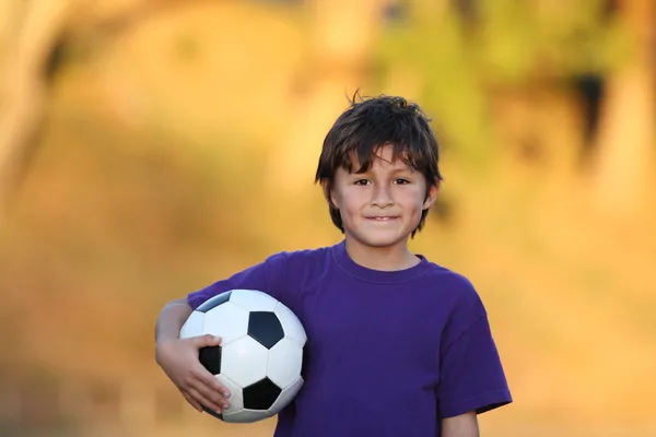 Jongen met voetbal bij zonsondergang Rechtenvrije Stockfoto's