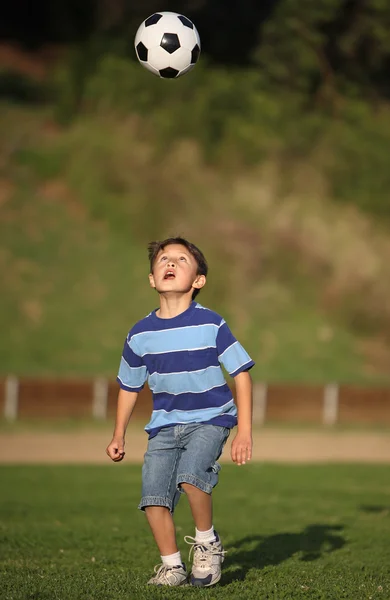 Latino niño jugando con pelota de fútbol Imágenes de stock libres de derechos