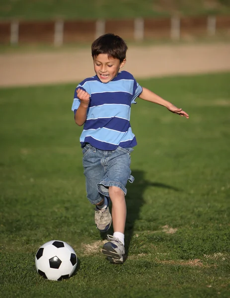 Latino niño jugando con pelota de fútbol Fotos de stock