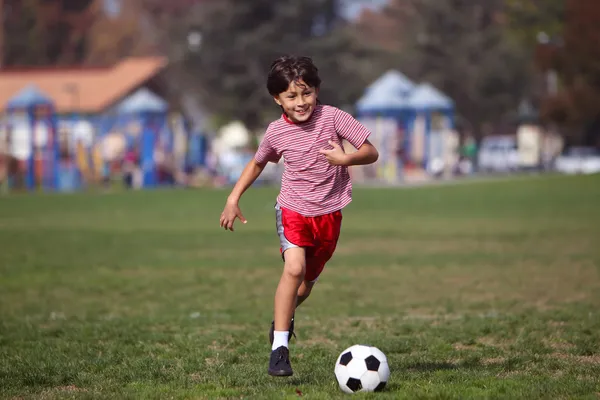 公園でサッカーをしている少年は — ストック写真