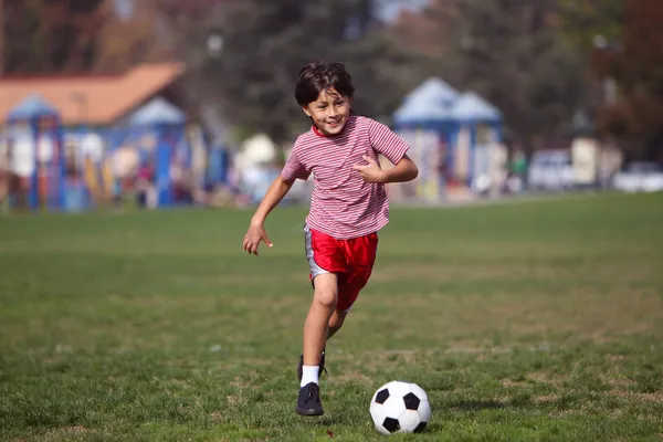 公園でサッカーをしている少年は ロイヤリティフリーのストック画像