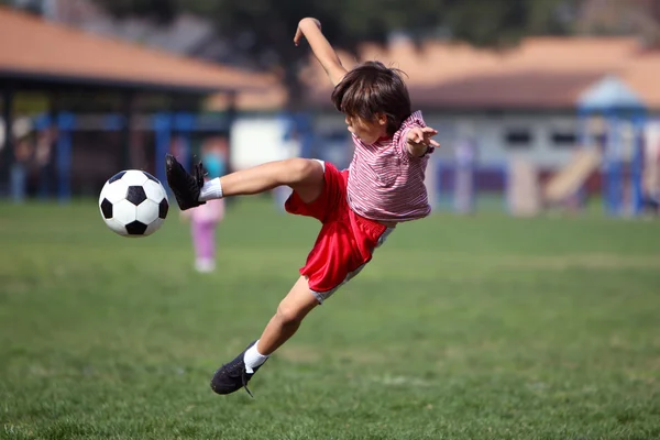 Niño jugando al fútbol en el parque Imagen de stock