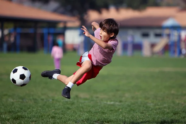 Niño jugando al fútbol en el parque Fotos de stock libres de derechos