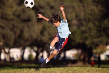 Young boy kicking a soccer ball in the park