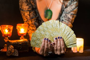 Tarot kartları gösteren bir kadının ellerinin ayrıntıları. Tarot kartlı kehanet oturumu kavramı.