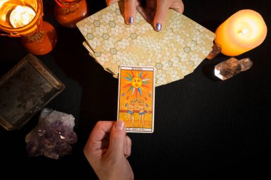 Bir kadının ellerinin tarot kartlarını gösterirken diğer elinin 