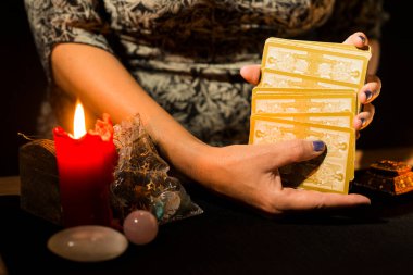 Tarot kartları karıştıran bir kadının ellerinin ayrıntıları. Tarot kartlı kehanet oturumu kavramı.