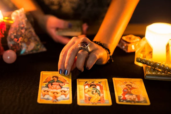 Falcılık seansı sırasında bir kadının ellerinin siyah kart masasına tarot kartları koymasının ayrıntıları. Tarot kartlı kehanet oturumu kavramı.