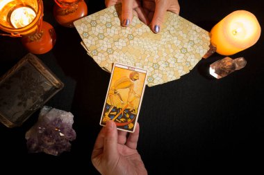 Bir kadının ellerinin tarot kartlarını gösterirken diğer elin 