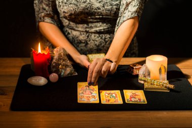 Falcılık seansı sırasında bir kadının ellerinin siyah kart masasına tarot kartları koymasının ayrıntıları. Tarot kartlı kehanet oturumu kavramı.